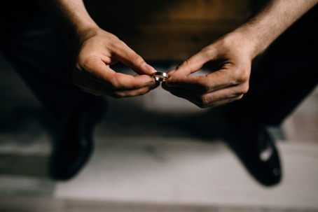 A man's hands hold a wedding ring.