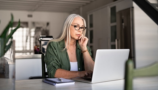 an older woman looks at her laptop