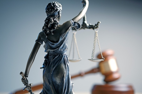 The image shows a statue of Lady Justice with scales and a gavel, representing law and legal matters.