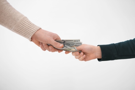 A person handing over the dollar bills to another person